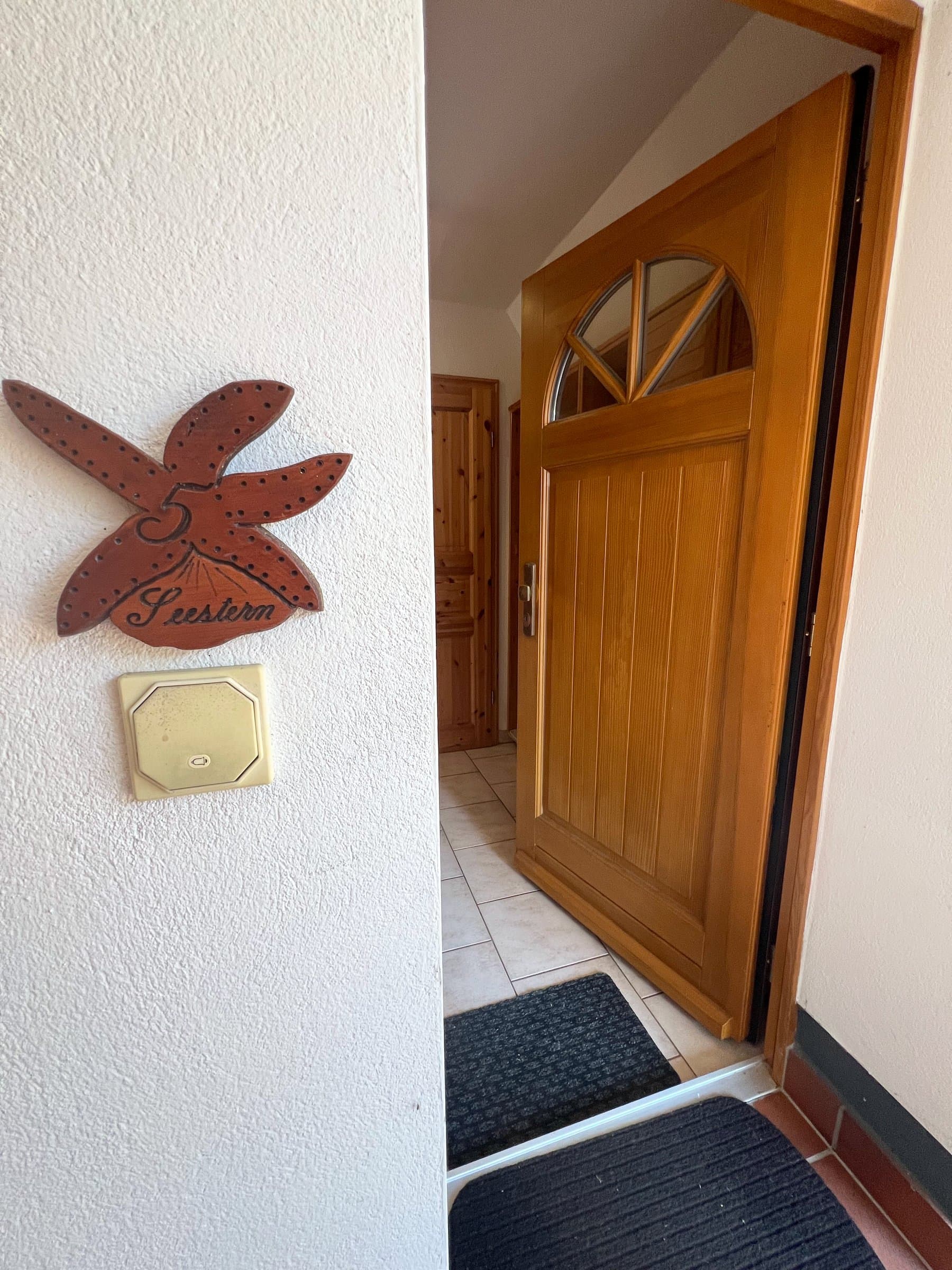 Geöffnete Holztür mit halbrundem Fenster; daneben an der Wand ein hölzerner Seestern mit der Zahl 5 und dem Schriftzug Seestern