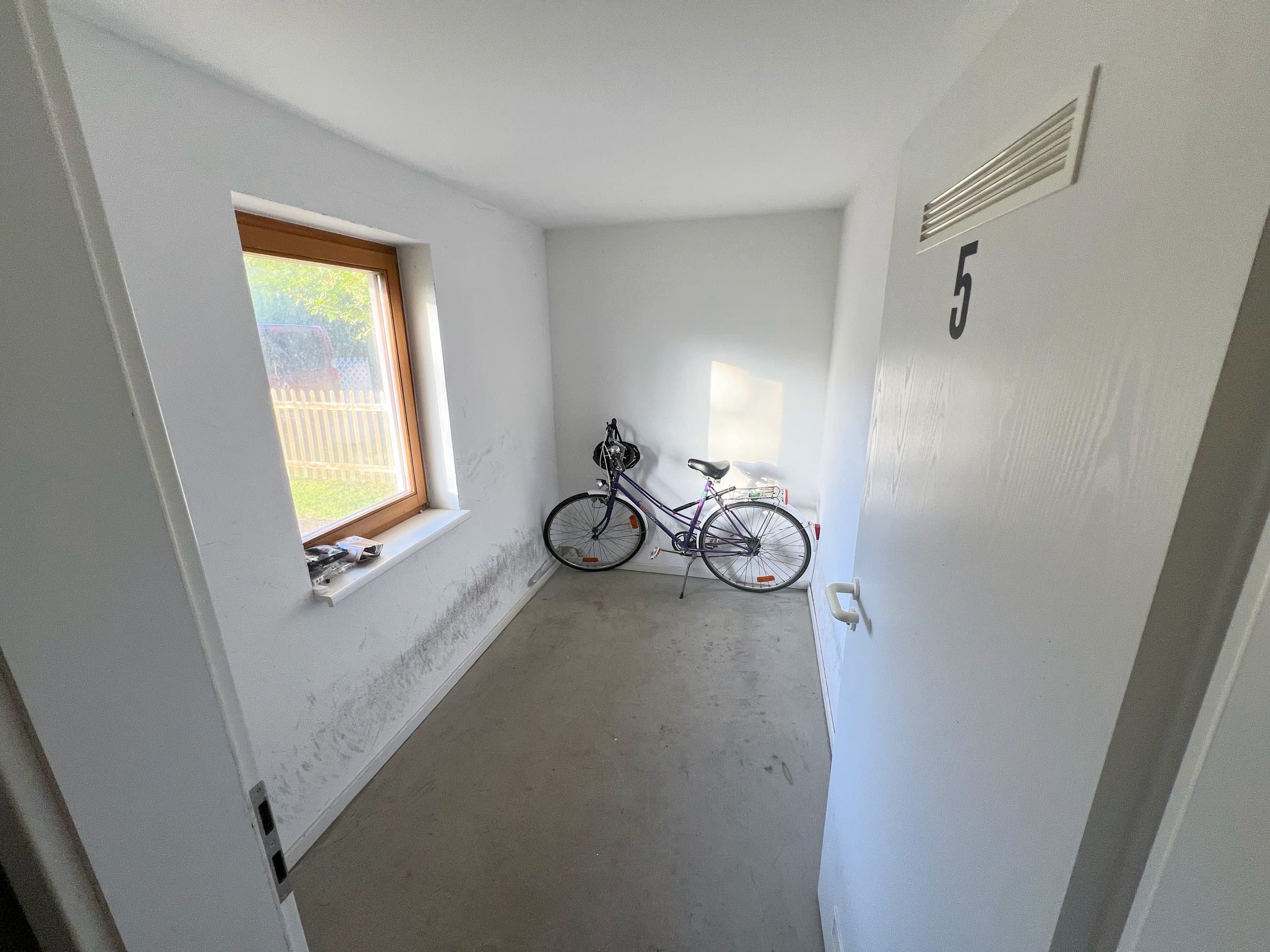 Schmaler Fahrradraum mit Fenster, an der Wand ein abgestelltes Fahrrad