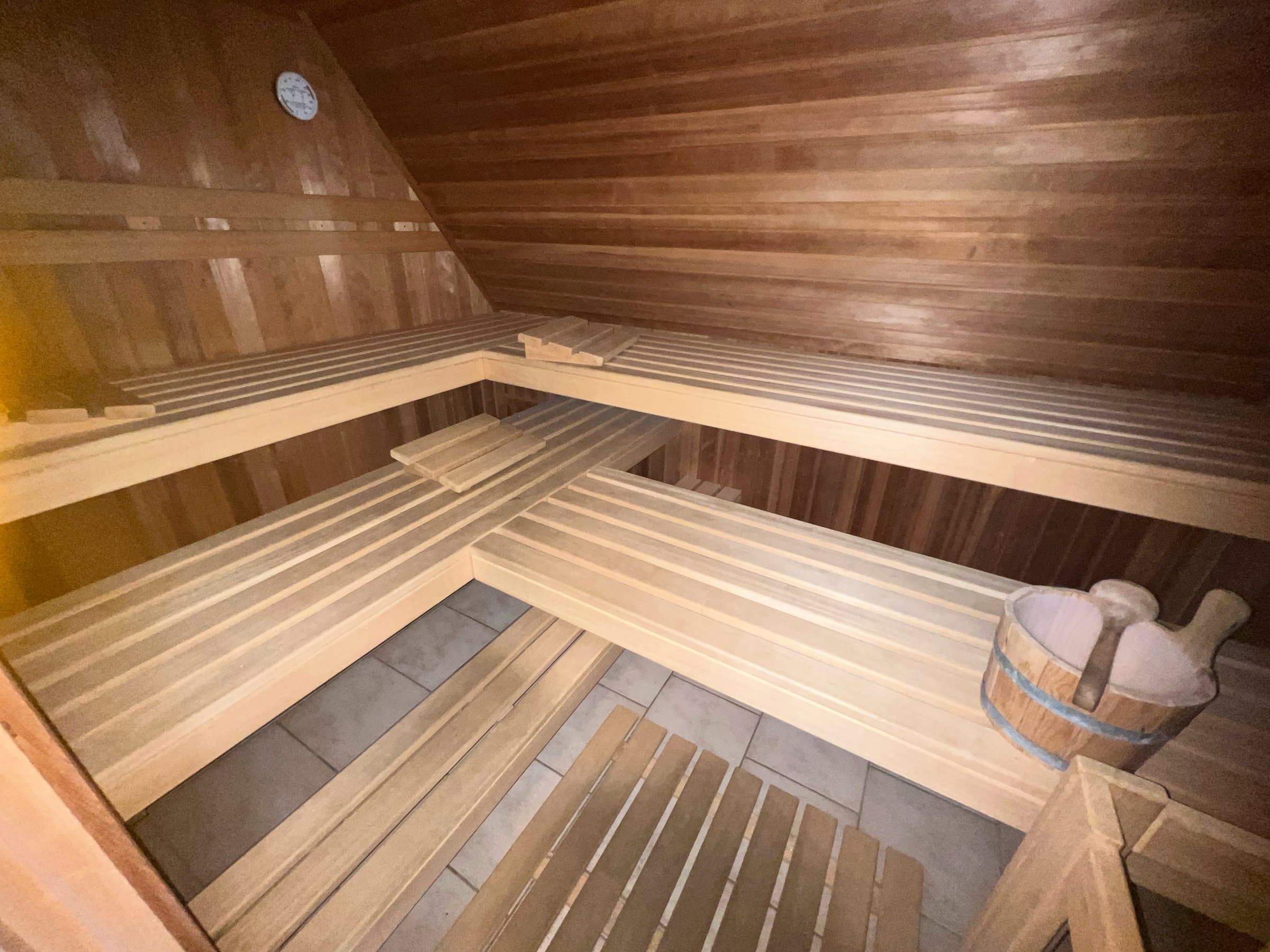 Holzsauna mit Liegebänken auf zwei Ebenen und Aufgusskübel mit Kelle